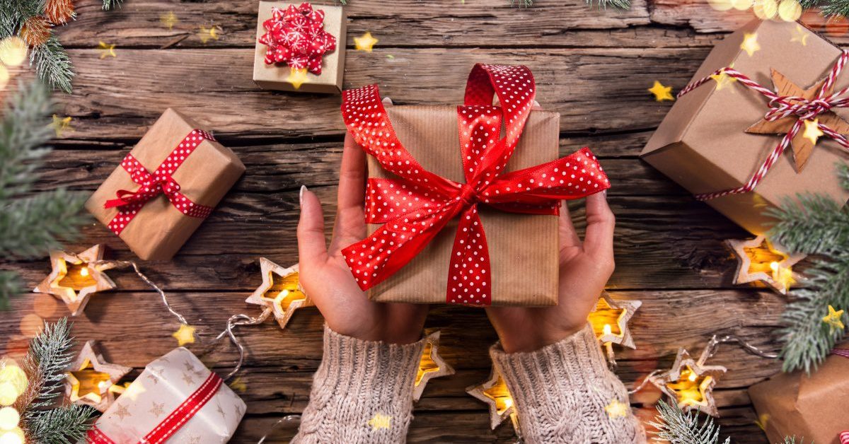 Top view of woman hands with gift box on wooden table.